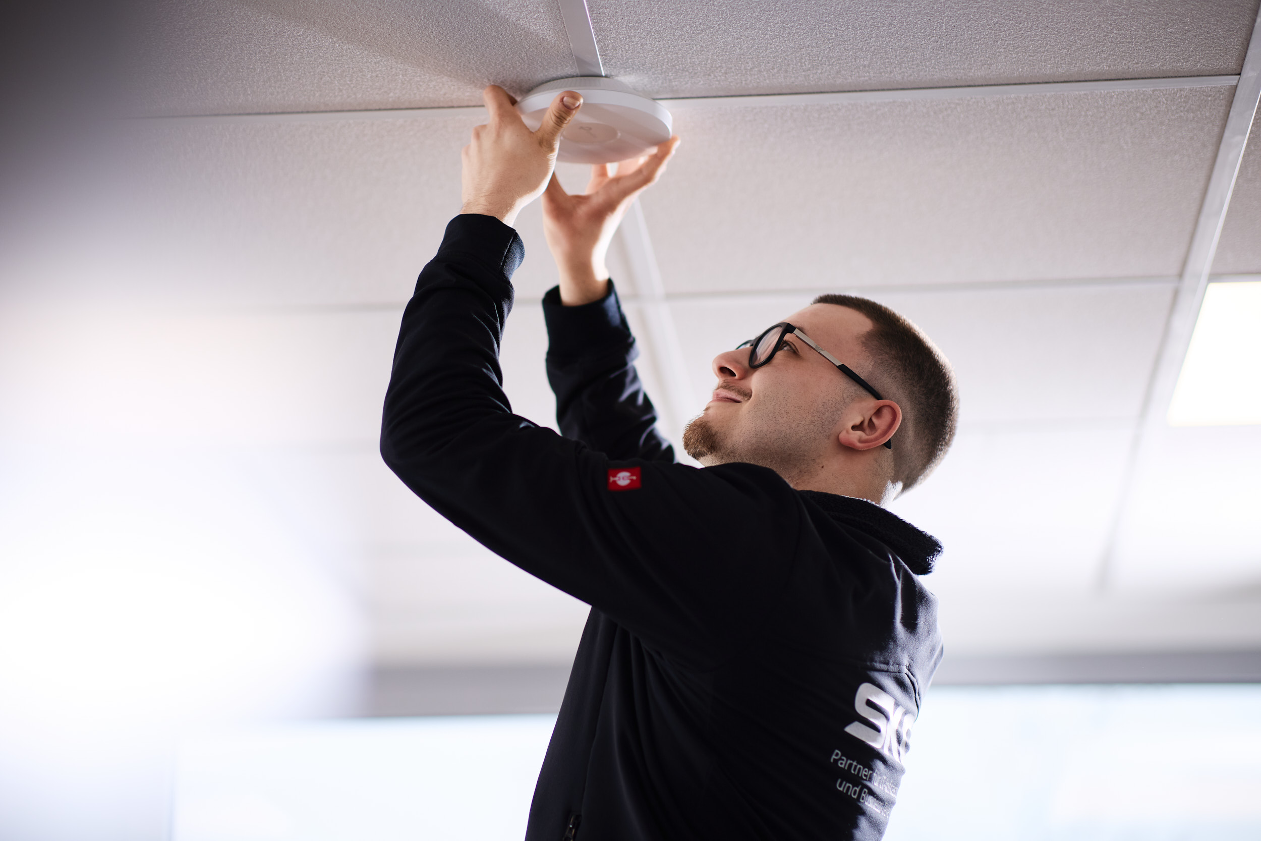 SKC Mitarbeiter installiert einen Access-Point für eine professionelle Netzwerklösungen